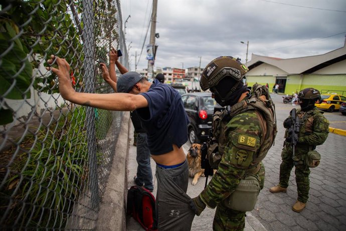 11 January 2024, Ecuador, Quito: A soldier searches a man in front of the Carapungo market in Quito. Elite teams from the Ecuadorian armed forces carry out anti-crime patrols in conflict-prone sectors of the city of Quito. They are looking for weapons, 