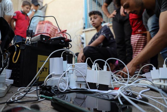 Archivo - Imagen de archivo de varias personas cargando sus teléfonos móviles en Jan Yunis, en el sur de la Franja de Gaza.