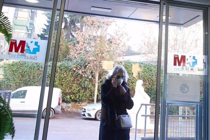 Una mujer entra con mascarilla a un centro de salud.