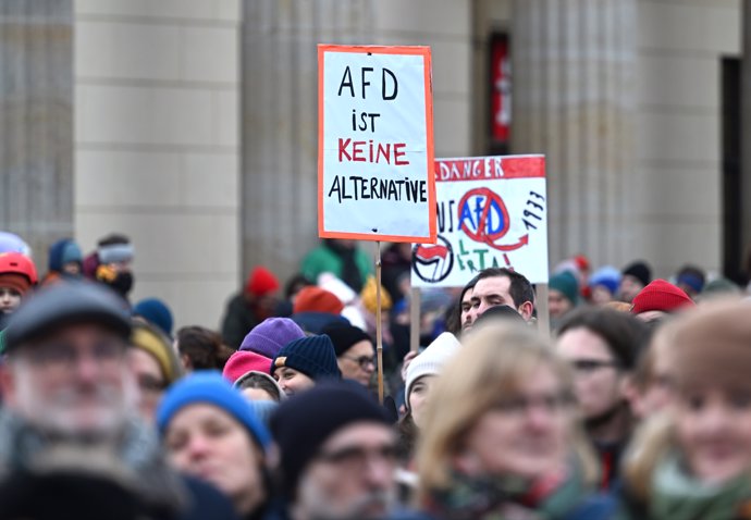 14 January 2024, Berlin: A protester holds a poster reading "AfD is no alternative" during a demonstration against the right at the Brandenburg Gate under the slogan "Defend democracy". Photo: Soeren Stache/dpa