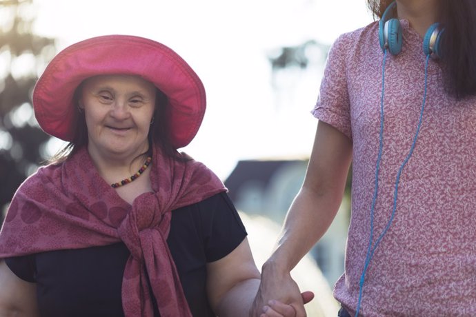 Archivo - Woman with Down Syndrome and her friend walking in a park.