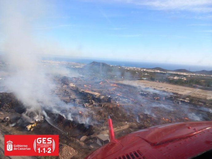 Un helicóptero del GES sobrevuela el incendio de una planta de compostaje en Arona