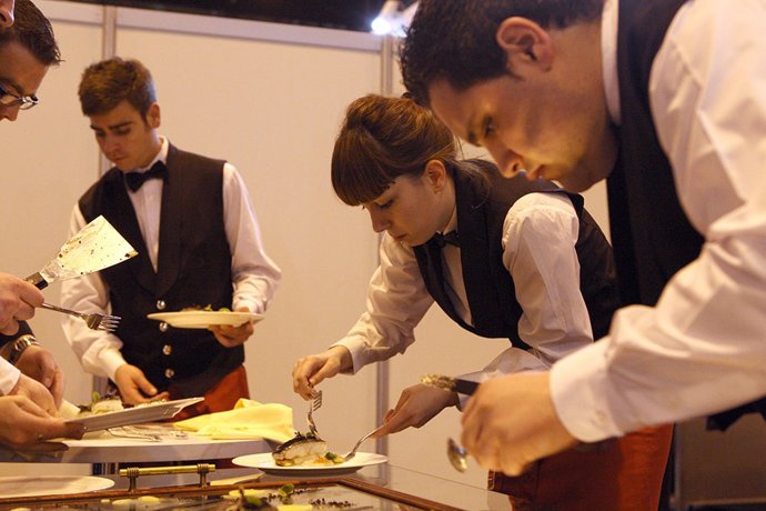 Archivo - Jóvenes trabajando en el sector servicios