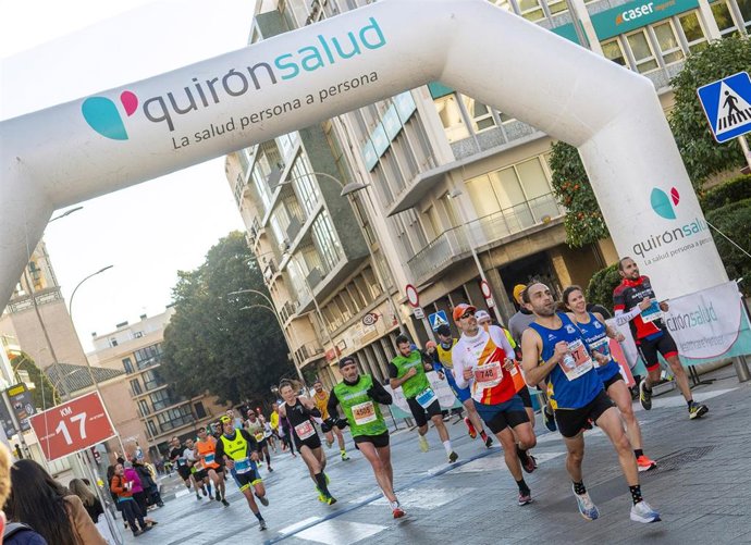 Archivo - Corredores cruzan un arco publicitario de Quirónsalud en el Medio Maratón de Sevilla