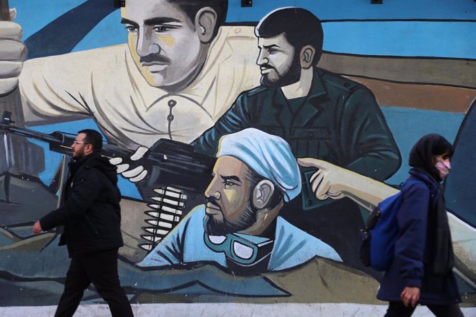 January 17, 2024, Tehran, Iran: An Iranian man and woman walk past a mural in downtown Tehran.