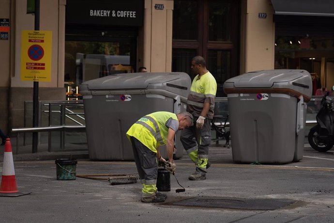 Archivo - Varios operarios asfaltan un tramo de carretera, a 10 de mayo de 2023, en Barcelona