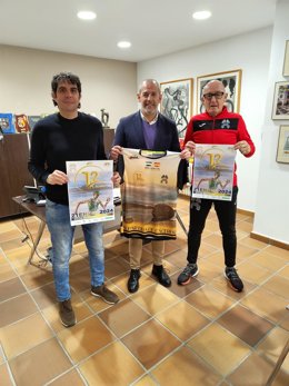El alcalde de Malpartida de Cáceres, Álfredo Aguilera, en el centro, con el cartel de la prueba.