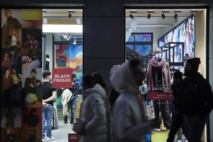 Archivo - Varias personas pasan por delante de los comercios que anuncian los descuentos del Black Friday, a 23 de noviembre de 2022, en Madrid (España).