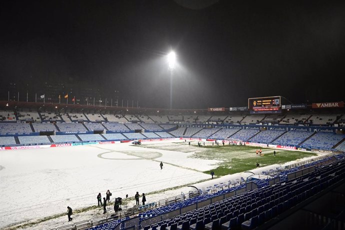 La nieve cubre el césped del estadio del Real Zaragoza, la Romareda, a 19 de enero de 2024, en Zaragoza, Aragón (España). El encuentro, planificado para este viernes 19 de enero a partir de las 20.30, se atrasó primero y se suspendió después tras la ins