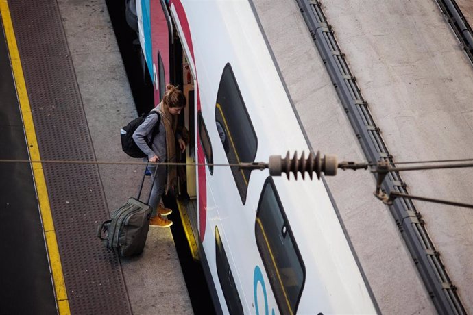 Una mujer entra en el tren con su maleta, durante la operación salida con motivo de las fiestas navideñas, en la estación de Atocha, a 22 de diciembre de 2023, en Madrid (España). Los destinos más solicitados por los ciudadanos para viajar en tren estas