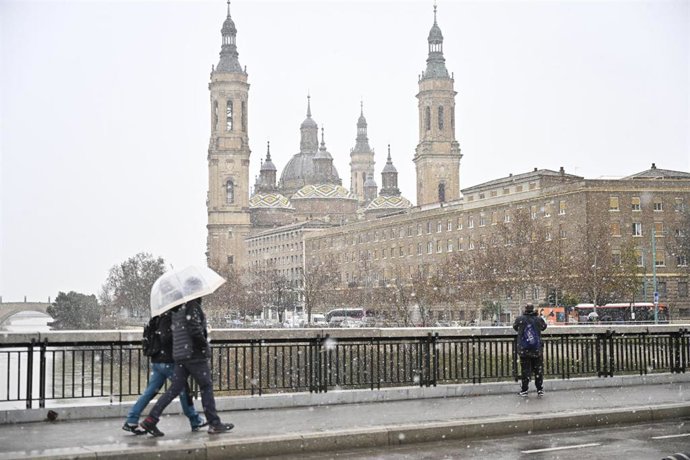 Archivo - Varias personas caminan por la calle bajo la nieve, a 19 de enero de 2024, en Zaragoza, Aragón (España). 