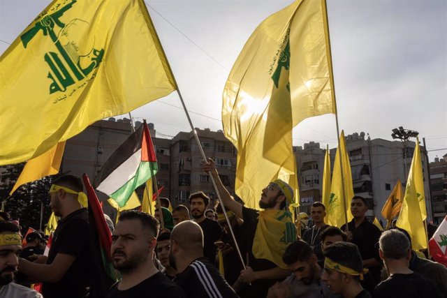 Archivo - Un grupo de personas con banderas del partido-milicia chií Hezbolá en la capital de Líbano, Beirut, durante un discurso televisado del líder del grupo, Hasán Nasralá (archivo)