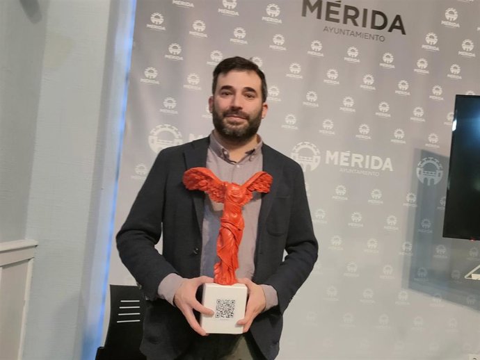 El delegado de Turismo, Felipe González, sujeta la recreación de la Victoria de Samotracia con el código QR con toda la información de Mérida durante la presentación de la programación de la ciudad en Fitur 2024.