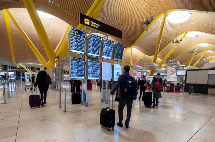 Archivo - Varias personas observan las salidas de los vuelos con motivo de la operación salida en el puente de diciembre, en el Aeropuerto Adolfo Suárez-Madrid Barajas, a 5 de diciembre de 2023, en Madrid (España). 