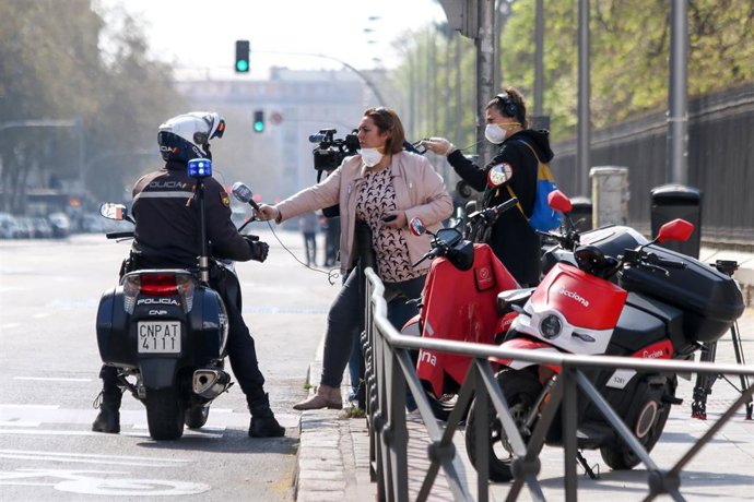 Archivo - Una periodista pregunta a un policía nacional durante la crisis del coronavirus en Madrid a 15 de marzo de 2020.