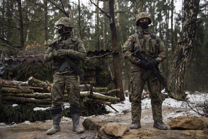 Archivo - 27 January 2022, Poland, Tolcze: Armed border guards are seen guarding the border line with Belarus during the construction works. Poland has started building wall on its eastern border intended to block migrants pushed by Belarus, in what the