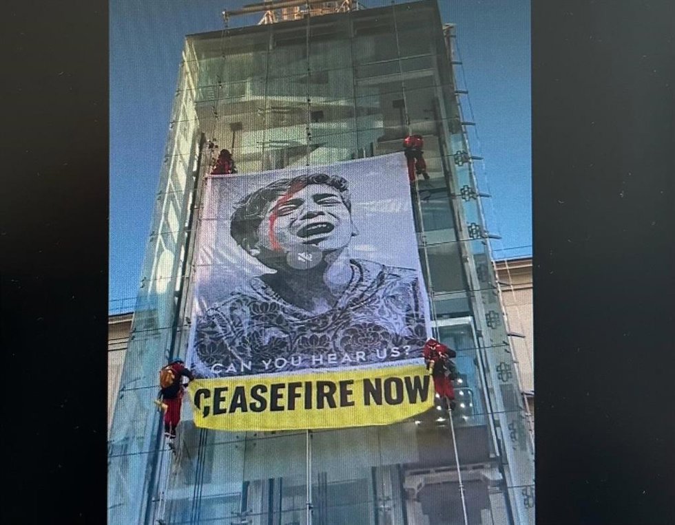 Activistas de Greenpeace cuelgan una pancarta pidiendo un "Alto el fuego ya" en el Museo de Arte Reina Sofía
