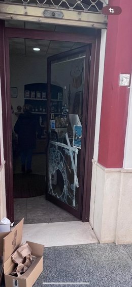 Imagen de la puerta de un local de Écija con la cristalera fracturada