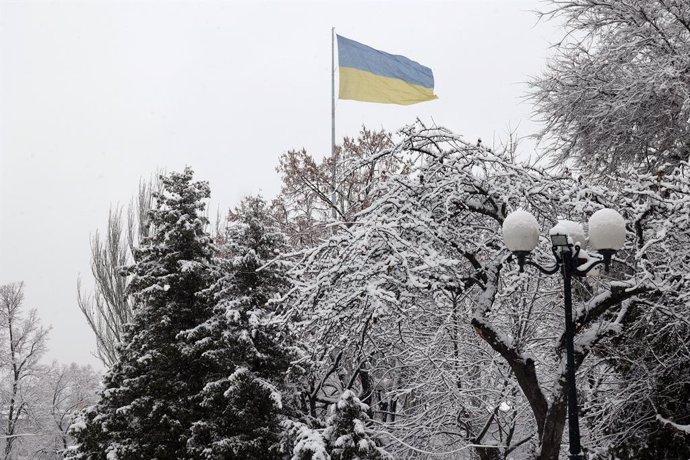 Archivo - December 12, 2023, Kharkiv, Ukraine: KHARKIV, UKRAINE - DECEMBER 12, 2023 - A Ukrainian flag is seen behind the trees covered in snow in winter, Kharkiv, northeastern Ukraine.