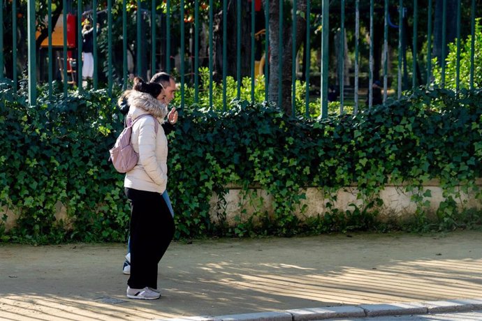 Personas abrigadas pasean por el Parque de María Luisa,  en un día frío y el soleado a la vez, a 27 de diciembre del 2023 en Sevilla (Andalucía, España). 