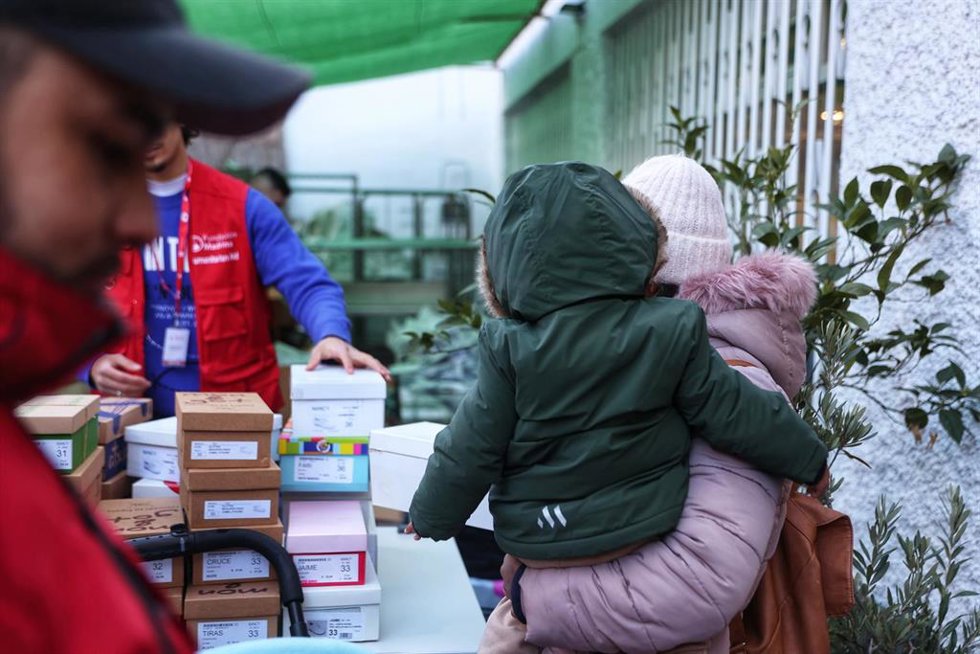 Archivo - Una mujer con un niño en brazos recibe ropa de invierno y zapatos que la Fundación Madrina entrega a familias en riesgo de vulnerabilidad en la sede de la Fundación Madrina.