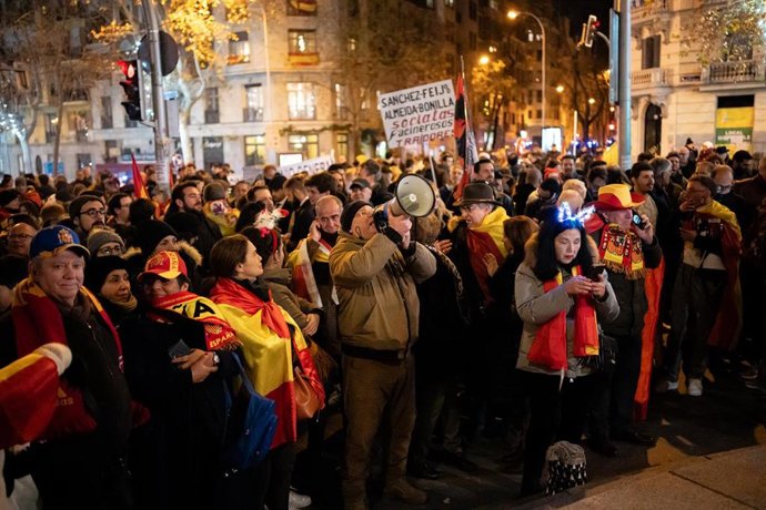 Decenas de personas con bufandas y banderas de España celebran la entrada del año nuevo, en la calle Ferraz, a 1 de enero de 2024, en Madrid (España). Revuelta, la organización juvenil de la órbita de Vox convocante de las concentraciones en Ferraz, ha 