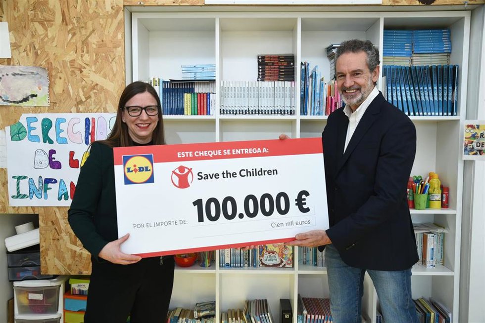 Michaela Reischl entrega el cheque de la venta solidaria de flores de pascua al director general de Save the Children, Andrés Conde.