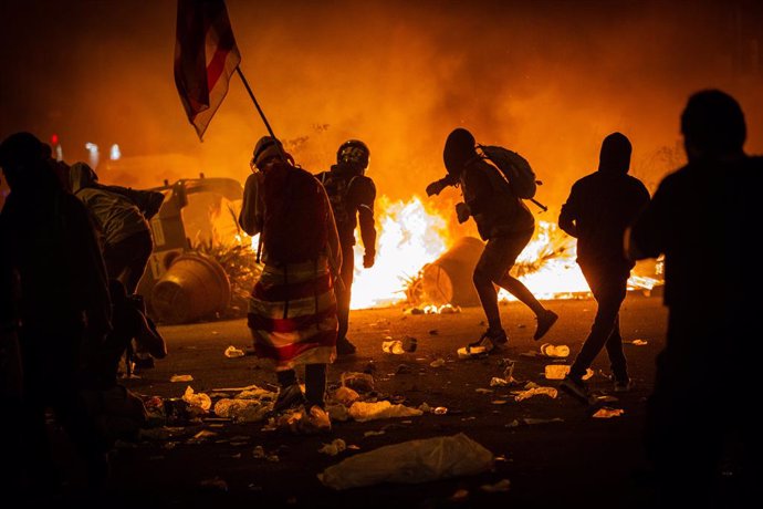 Archivo - Varios manifestantes frente al fuego de una hoguera durante los disturbios en la Plaza de Urquinaona, en Barcelona a 18 de octubre de 2019.