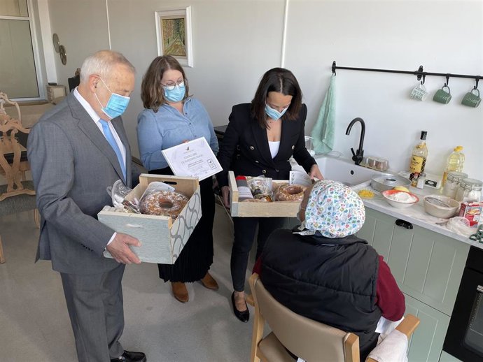 La consejera de Bienestar Social y Familia del Gobierno de Aragón, Carmen Susín, saluda a un residente en el taller de cocina.
