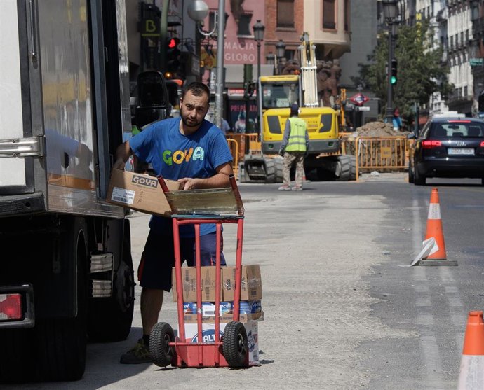 Archivo - Un trabajador descarga cajas de un camión.