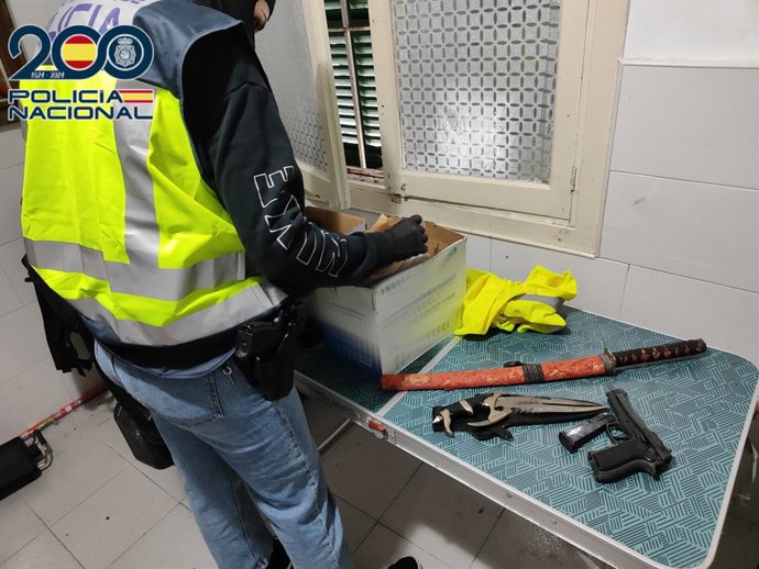 Un agente de la Policía Nacional junto a las armas intervenidas durante el registro.
