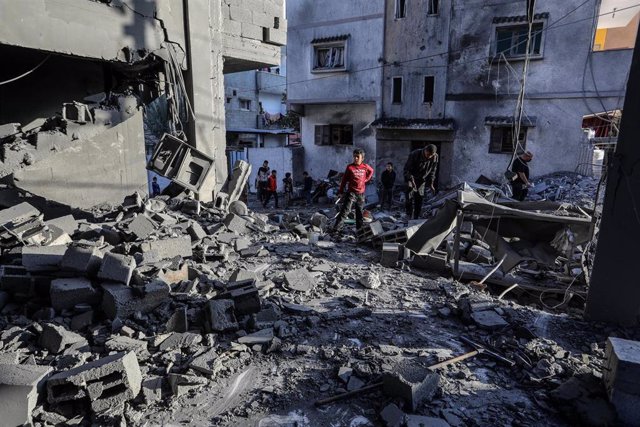 Ciudadanos palestinos frente a un edificio destruido en la Franja de Gaza