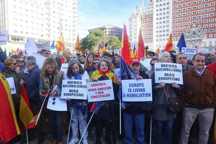 Varias personas sujetan carteles antes de una manifestación convocada por el PP, a 28 de enero de 2024, en Madrid (España). El PP se ha movilizado hoy para oponerse a los pactos entre el PSOE y el independentismo, tras el acuerdo firmado entre Junts y e