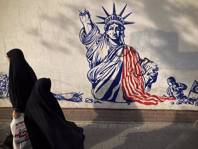 Archivo - October 25, 2023, Tehran, Iran: Iranian veiled women walk past a mural painting along the wall of the former US embassy.