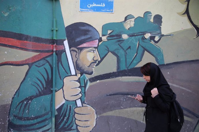 January 17, 2024, Tehran, Iran: An Iranian woman walks past a mural in downtown Tehran.