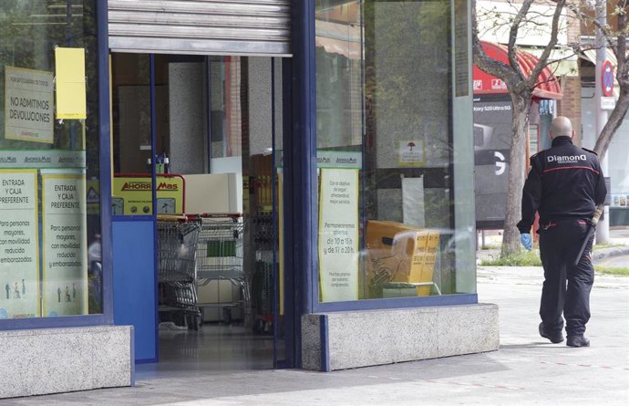Archivo - Un vigilante de seguridad controla las inmediaciones de un establecimiento del supermercado Ahorramás durante el día 34 del estado de alarma, en Madrid (España), a 17 de abril de 2020.