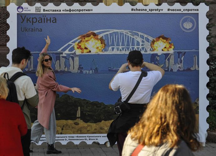 Archivo - October 8, 2022, Kyiv, Ukraine: People take photos against the background of the stamp layout, which depicts the burning Kerch bridge. On October 8, on the Crimean bridge connecting Russia and the peninsula occupied by it, after the explosion,