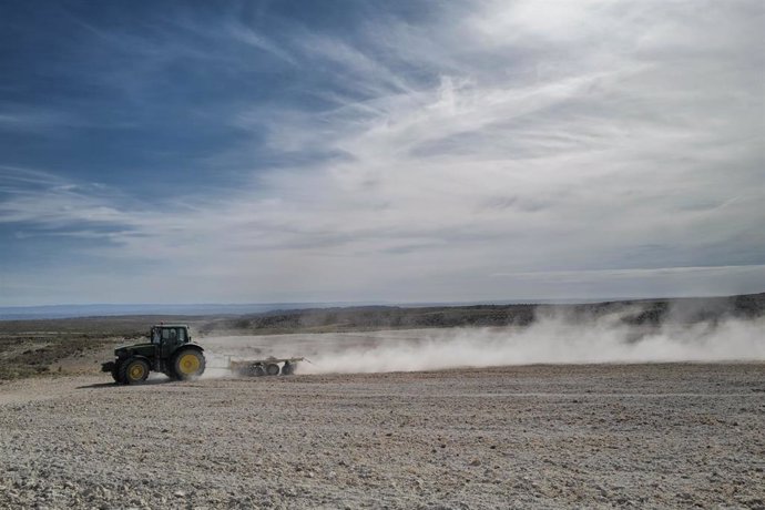 Archivo - Un tractor para arar la tierra en el campo de Belchite, 