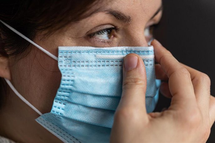 Archivo - Una mujer se coloca una mascarilla 