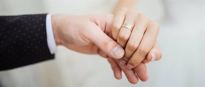 Una pareja cogida de la mano en su boda.