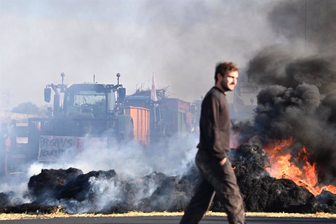 26 January 2024, France, Saint-Jean-De-Vedas: French farmers burn bales of straw while blocking the A9 highway during a demonstration against falling incomes, European environmental regulations and standards that they believe are getting out of hand. Phot
