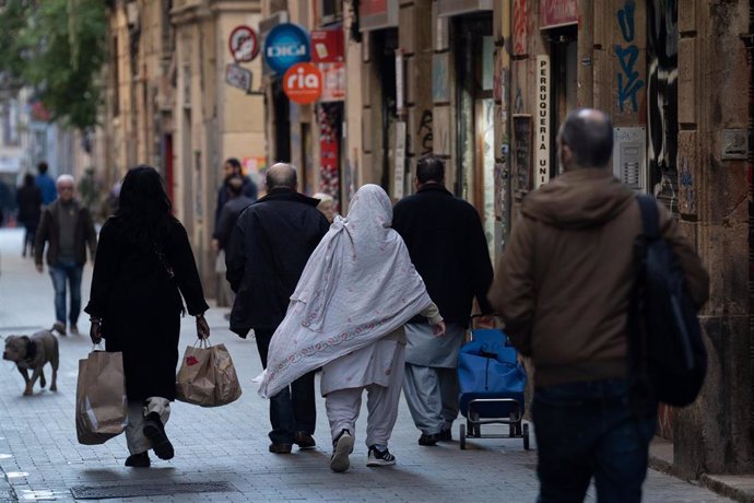 Varias personas caminan cargadas por una calle, a 24 de enero de 2024, en Barcelona, Catalunya (España). 