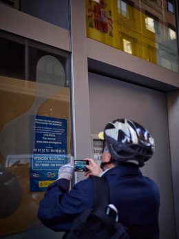 Archivo - Un hombre saca una foto a un anuncio en una oficinas de empleo en Pamplona.