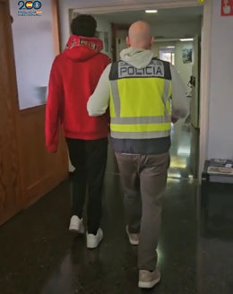 Un agente de la Policía Nacional junto a uno de los detenidos.