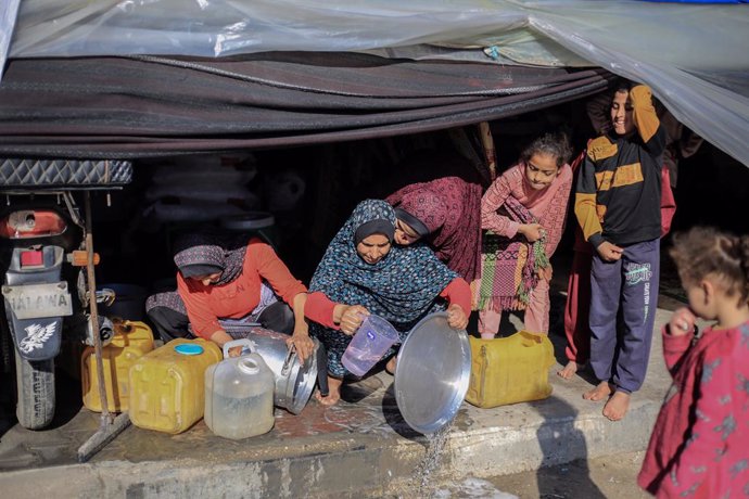 04 February 2024, Palestinian Territories, Rafah: Displaced Palestinian women from the north of Gaza City clean cooking pots outside a temporary tent established on the sidewalk on a street in Rafah because there is no room for them in the camp areas. Pho