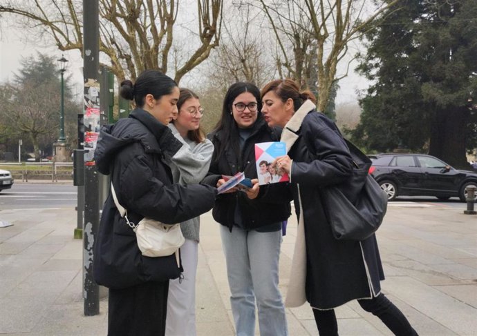 La candidata de Sumar Galicia, Marta Lois, reparte folletos electorales a unas jóvenes en Santiago de Compostela