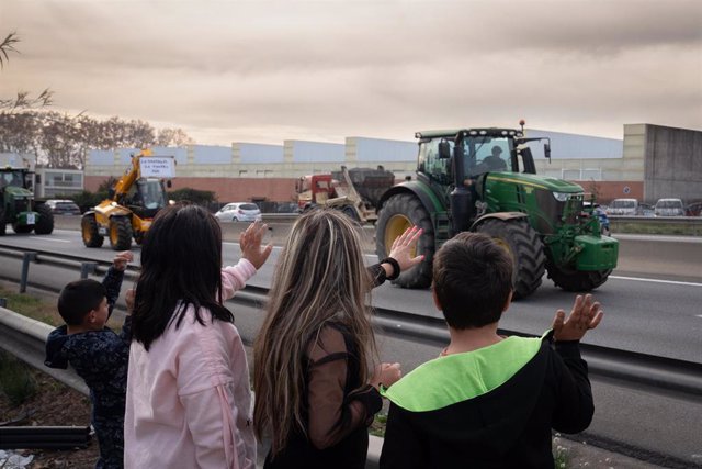 Cuatro personas saludan a varios tractores que han cortado la carretera C-17, sentido sur, a la altura de Parets del Vallès.