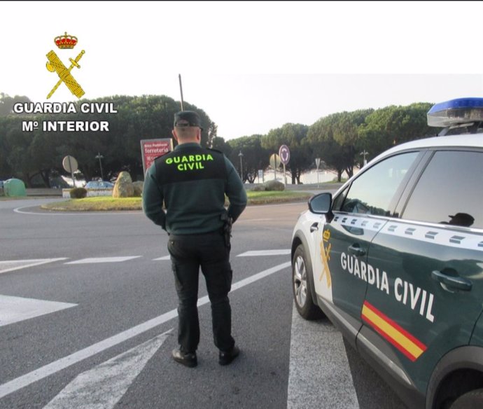 Agente de la Guardia Civil junto a su vehículo