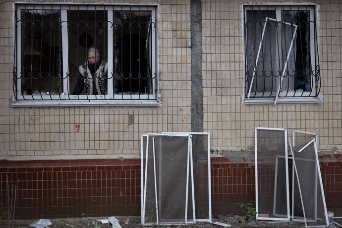 Archivo - 13 December 2023, Ukraine, Kiev: A resident looks out of a window of her apartment building damaged during a Russian missile strike in Kiev. At least 53 people were injured after missile debris fell in several districts of the Ukrainian capital 
