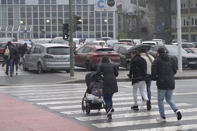 Archivo - Varias personas cruzan un paso de peatones tratando de refugiarse de la lluvia,